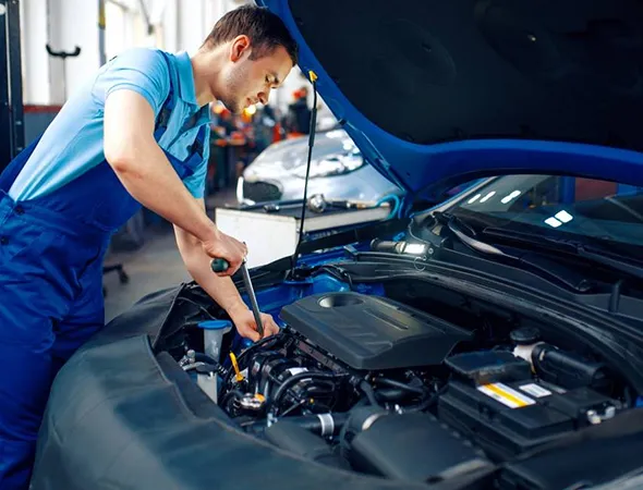 A technician is focused on car repair, working meticulously on the engine to ensure optimal performance.
